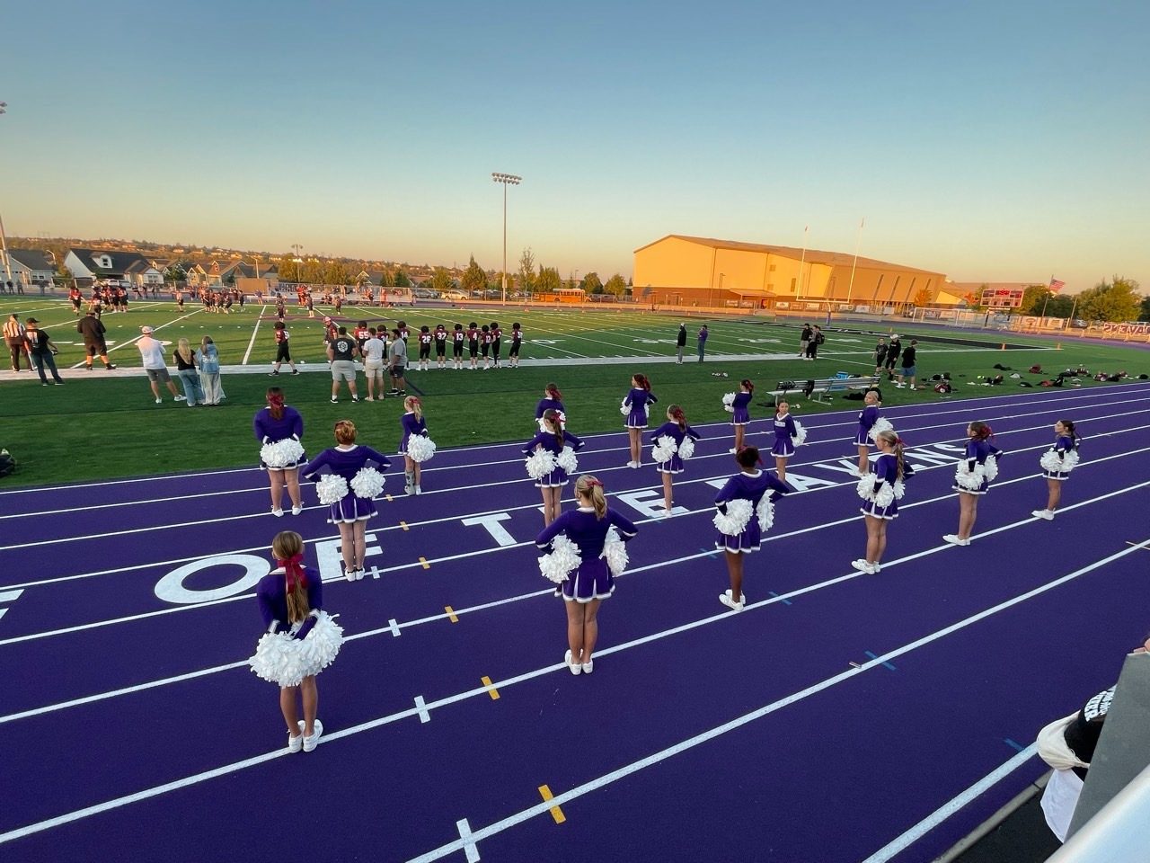 Junior cheer squad lined up on the sideline track at a game